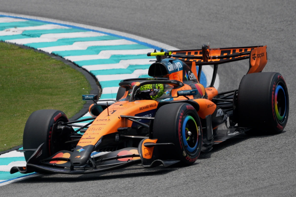 Orange McLaren turning beside the turquoise and white kerb at Sepang Circuit