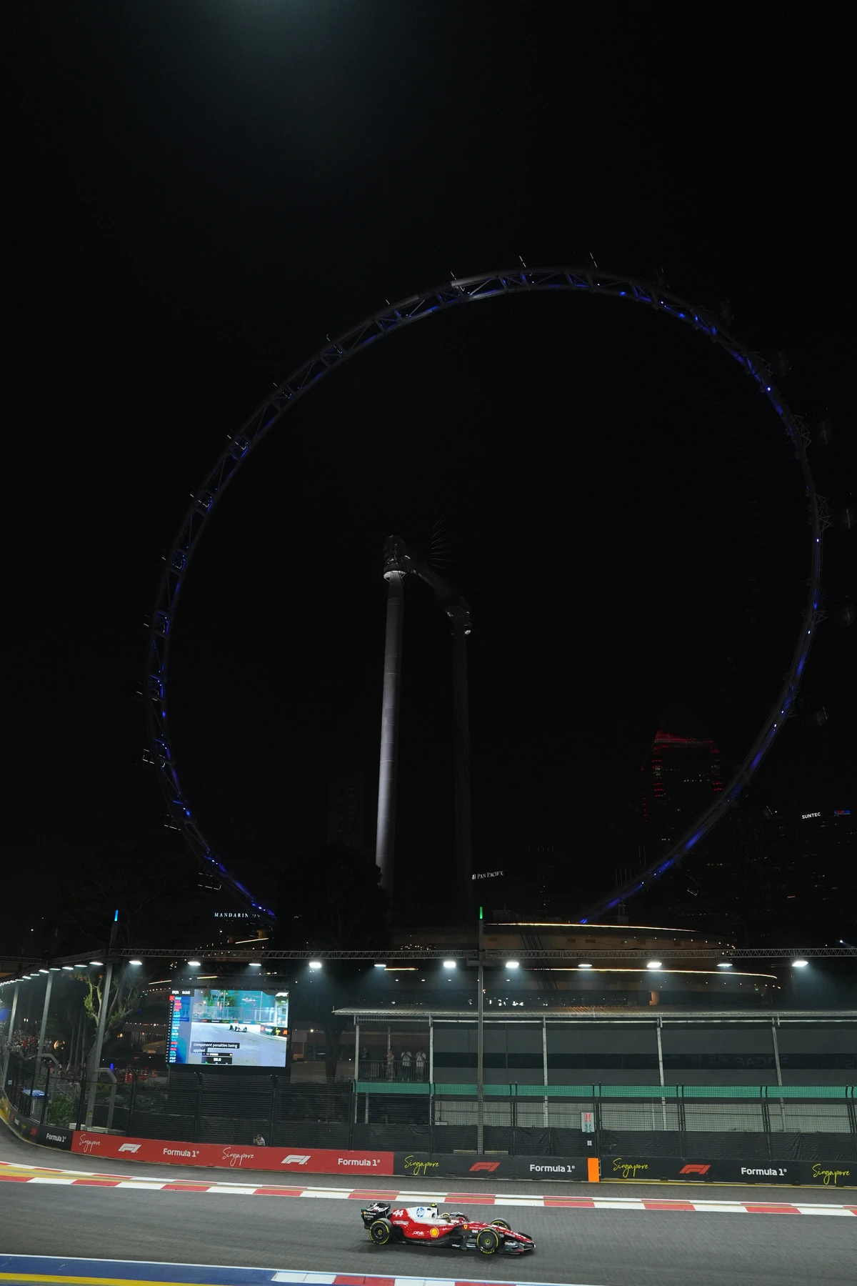 Vertical view of the Singapore Flyer at night with a red Ferrari on the circuit below